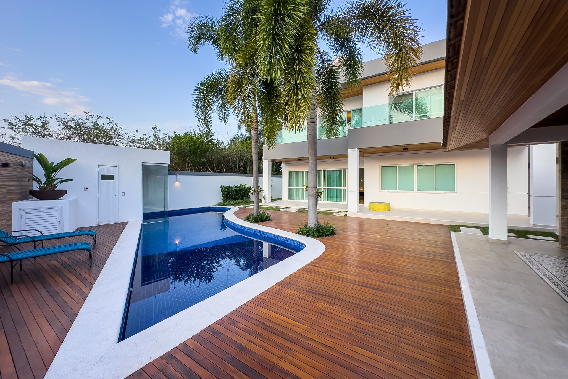 Piscina com deck de madeira e vista da casa